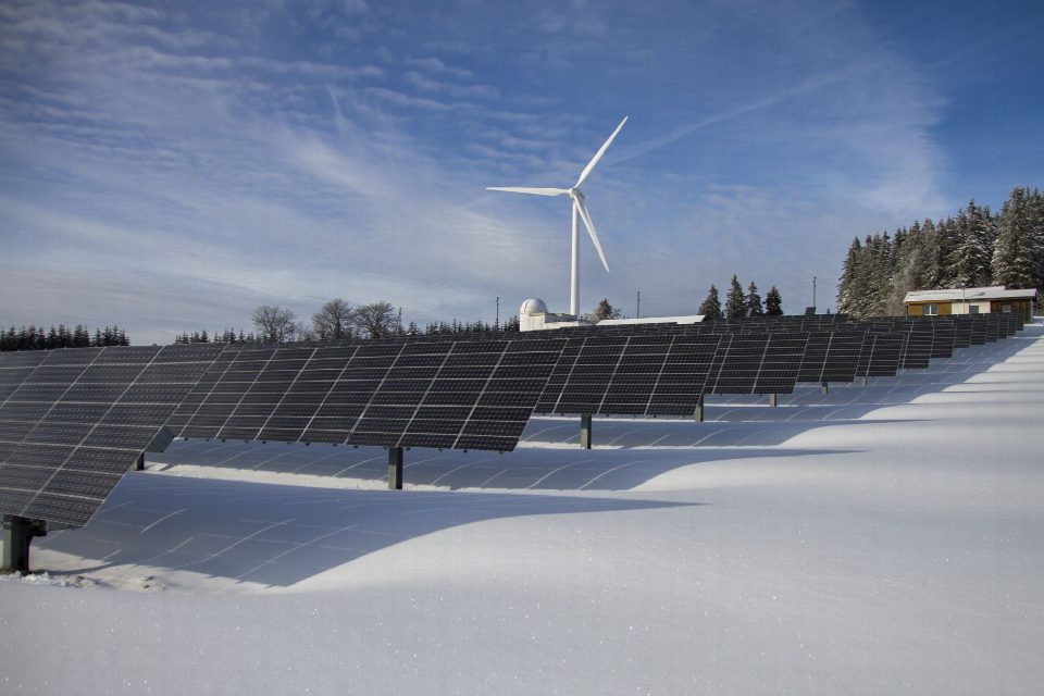 Solar panels and wind turbine in a snowy landscape, showcasing renewable energy sources. Solar panels and wind turbine in a snowy landscape, showcasing renewable energy sources.