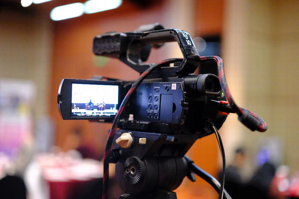 Close-up of a camcorder recording a business conference indoors. Close-up of a camcorder recording a business conference indoors.